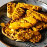 A delicious plant-based dish with crispy vegan chick'n tenders on top of whole grain waffles, drizzled with a zesty maple sriracha mustard sauce.